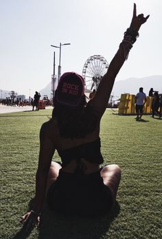 a woman sitting in the grass with her arms up