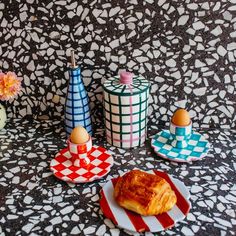 three colorful vases sitting on top of a black and white table cloth next to each other