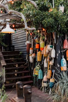 an outdoor area with many hanging objects and plants on the wall, along with stairs