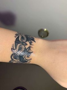 a woman's arm with a dragon tattoo on her left arm and silver glitters on the wrist