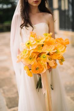 a bride holding a bouquet of yellow flowers