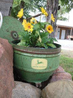 a potted plant sitting on top of a rock next to a green container filled with flowers