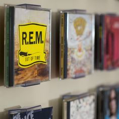 cd cases are hanging on the wall with rem out of time stickers attached to them