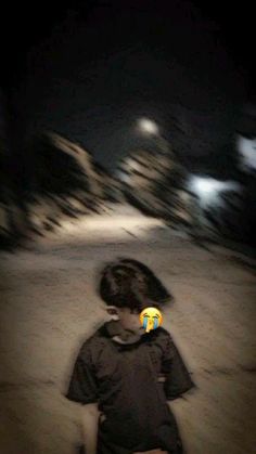 a young boy sitting on top of a snow covered slope at night with his back turned to the camera