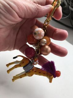 a hand holding a giraffe keychain with beads and charms on it