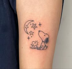 a small tattoo on the arm of a person with a dog and stars around it