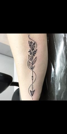 a woman's leg with an arrow and flower tattoo on the left side of her leg