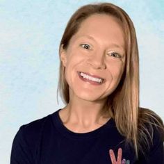 a woman with long hair wearing a peace sign t - shirt smiles at the camera