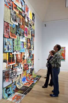 two people standing in front of a wall covered with posters