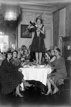 an old black and white photo of women sitting around a table