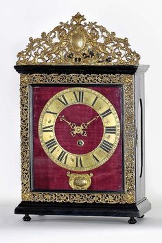 an ornate clock with roman numerals and gold trimming on red velvet cover