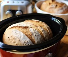 three loaves of bread sitting in an electric crockpot on a wooden table