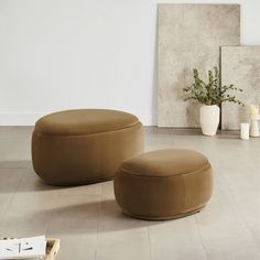 two round stools sitting next to each other on the floor in front of a white wall