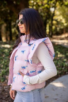 Light pink quilted puffer vest with ruffled shoulders and blue floral print Stay cozy and stylish in our Floral Trends pink puffer vest. This light pink vest features a playful blue floral print, ruffled shoulders, and convenient front pockets. Perfect for adding a pop of color to any outfit - show up, and show out! True to size fit; slightly cropped Model is 5'3" wearing a small Fabric doesn't contain stretch Zipper front closure Sleeveless with ruffle shoulders Front pockets Small length: 21" Cute Bonfire Outfits, Light Pink Vest, Bonfire Outfit, Bff Hoodies, Preppy Vest, Pink Puffer Vest, Germany Trip, Trendy Vest, Puffer Vests