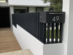 a black and white mailbox sitting on the side of a building next to a fence