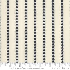 a white and black striped fabric with an arrow pattern on the bottom, in front of a ruler