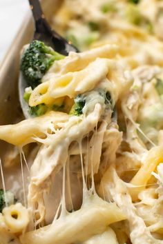 a casserole dish with broccoli and cheese being scooped from the casserole