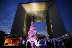 people standing in front of a tall building with lights on the outside and around it