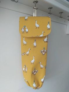 a yellow bag with ducks and geese on it hanging from a hook in a closet