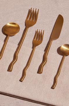 five golden forks and spoons are lined up on a table