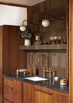 a kitchen with wooden cabinets and marble counter tops, gold faucets and brass fixtures