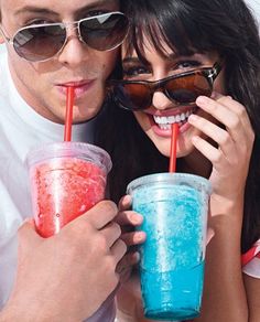 a man and woman are holding up drinks with straws in their mouths while posing for the camera