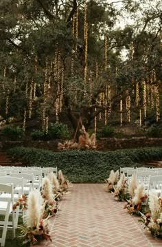 an outdoor ceremony setup with white chairs and flowers