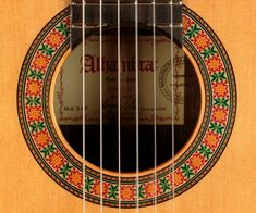 an acoustic guitar with a colorful design on the fret and label in the middle