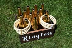 a wooden box filled with lots of bottles on top of green grass next to a rope