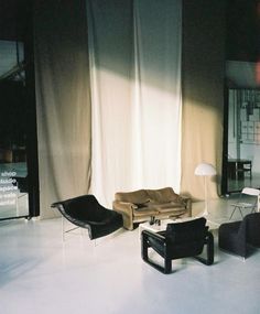 a living room filled with furniture next to a white wall and floor covered in curtains