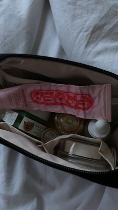 an open zippered bag filled with items on top of a bed