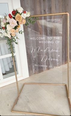 a welcome sign with flowers on it in front of a wooden wall