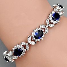 A beautiful piece of remarkable elegance, this exquisite bracelet will add a touch of sophistication to any wedding gown or formal ensemble. Adorned with flawless sapphire blue and clear cubic zirconia that capture the light from every angle with a perfectly translucent appeal, the bracelet is rhodium plated for a flawless finish which perfectly enhances the intricate detailing and conveys a modern take on old elegance. Length: 7.75" (approx. 19.6cm); Width: 0.5" (approx. 1.2cm). Closure is a se Blue Wedding Jewelry, Bridal Bracelet, Sapphire Blue, Wedding Gown, Rhodium Plated, Blue Sapphire, Wedding Jewelry, Wedding Gowns, Cubic Zirconia