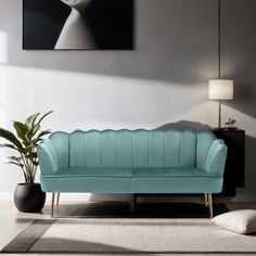 a living room with a blue couch next to a potted plant and a painting on the wall