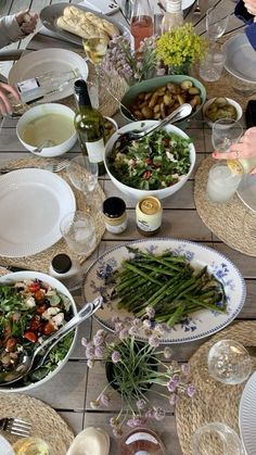 a group of people sitting around a table with plates and bowls of food on it