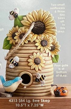 a birdhouse with sunflowers and bees painted on the side, sitting on a table