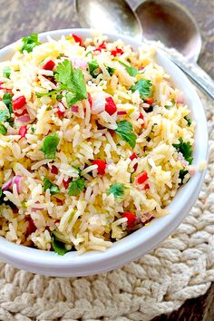 a white bowl filled with rice and garnished with cilantro, red peppers, and green onions