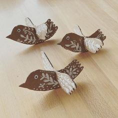 three paper birds sitting on top of a wooden floor