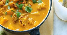 a bowl filled with curry and meat on top of a table