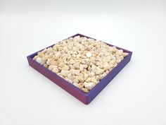 a purple bowl filled with rocks on top of a white table