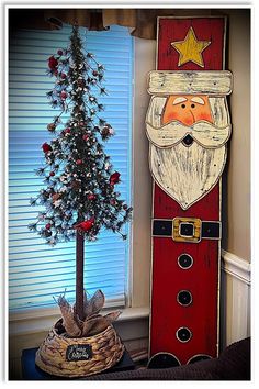 a wooden santa clause next to a christmas tree