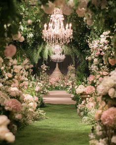 an archway with flowers and chandelier hanging from it's sides in front of a lush green lawn