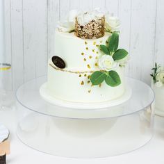 there is a white cake with gold decorations on the top and flowers on the bottom