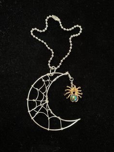 a necklace with a spider on it and a green stone in the moon's center