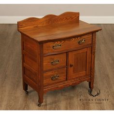 a wooden cabinet with three drawers on casteors and two doors, sitting on a hard wood floor