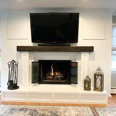 a fireplace with a flat screen tv above it and some lanterns on the mantles