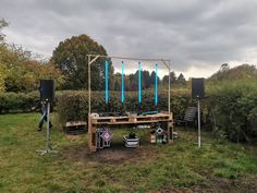 an outdoor stage set up in the middle of a grassy area with speakers and lights on it