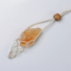 a piece of fruit is tied to a string on a white surface with a wooden bead