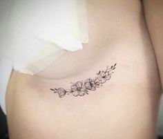 a woman's stomach with flowers and leaves tattoo on her left side ribcage