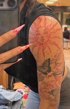 a woman with sun and butterfly tattoos on her arm